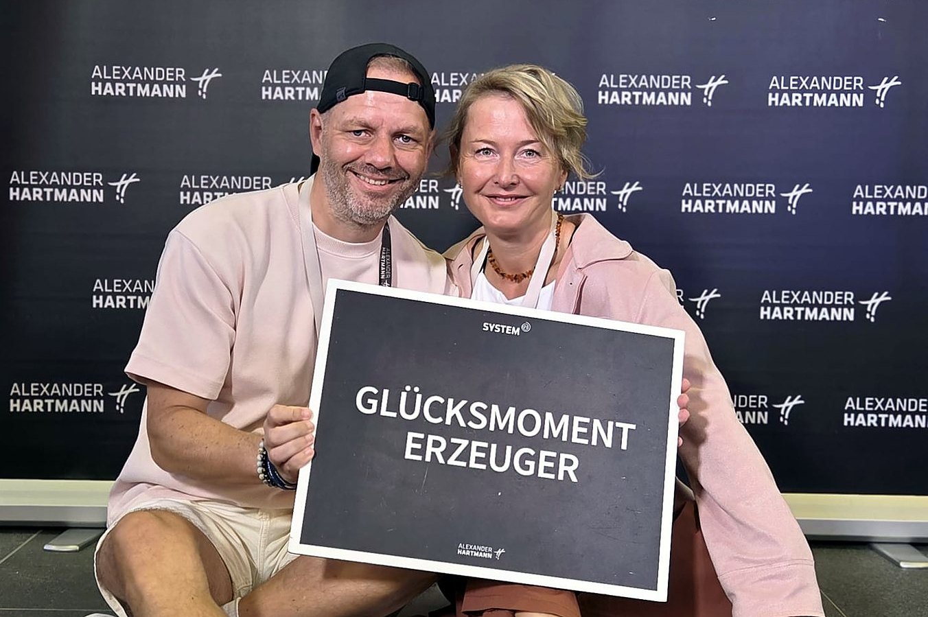 Ralf Hermann und Nicole Butschbach mit dem Schild „Glücksmoment-Erzeuger“ am Abschlusstag ihrer Hypnose-Ausbildung