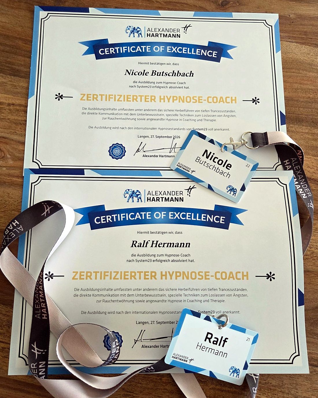 Die Zertifikate „Zertifizierter Hypnose-Coach“ von Nicole Butschbach und Ralf Hermann mit Namensschildern